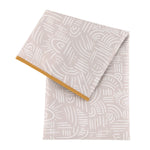 Bumkins Splat Mat: Wander is a beige, waterproof, machine washable mat with abstract white patterns and an orange trim.