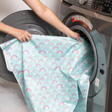 A person places Bumkins Splat Mat: Rainbows into an open front-loading washing machine.