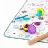 Close-up of colorful clay and toys on top of Bumkins Splat Mat: Floral on a white background.