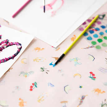 Close-up of colorful artwork and paintbrushes on Bumkins Splat Mat: Princess Magic.