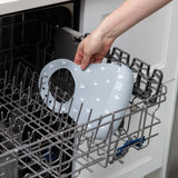 A person places Bumkins Silicone Bib: Hearts in the top rack of an open dishwasher.