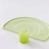 Bumkins Silicone Starter Cup: Sage sits in front of a green placemat on a white background.