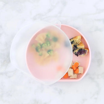 Bumkins Silicone Stretch Lid for Grip Dish 3 Section, Grip Plate covers a pink plate with pasta, veggies, and bread on a marble background.