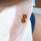 Close-up of two cereal rings in the pocket of a pink Bumkins Starter Bib 2 Pack: Floral & Lace.