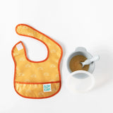 A Bumkins Starter Bib 2 Pack: Sunshine and Grounded lays on a white background next to a gray bowl of applesauce, spoon, and lid.