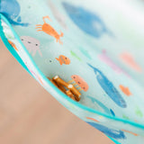 Close-up of a Bumkins Starter Bib 2 Pack: Ocean Life & Whale Tail with pretzels in the pocket.