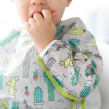 Close-up of a child wearing a Bumkins Sleeved Bib: Cacti with their fingers in their mouth.