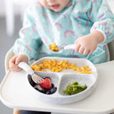 Close-up of a toddler in a high chair using Bumkins Spoon + Fork: Marble to enjoy mac & cheese, broccoli, and berries from a matching plate.