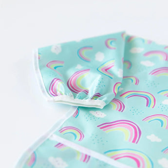 Close-up of Bumkins Sleeved Bib: Rainbows on a white background, with focus on the white elastic cuff on the sleeve.