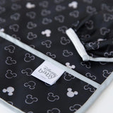 Close-up of Bumkins Sleeved Bib: Mickey Mouse Icon Black + White on a white background, with focus on the front pocket and elastic cuff.