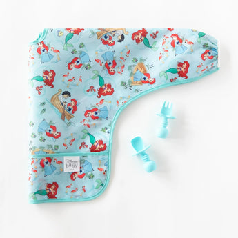 Bumkins Sleeved Bib: Ariel lays folded next to blue baby utensils on a white background.