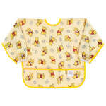 Bumkins Sleeved Bib: Winnie Loves Hunny features yellow waterproof fabric with playful Winnie the Pooh illustrations and a front pocket.