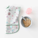 A floral bib lays folded next to Bumkins Grip Bowl Essential 4-Piece Mealtime Set: Gray with cereal and a pink cup on a white background.