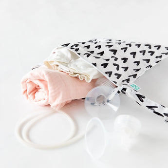 Bumkins Wet Bag: Hearts lays partially open on a white background with cloth diapers and breast pump parts spilling out.