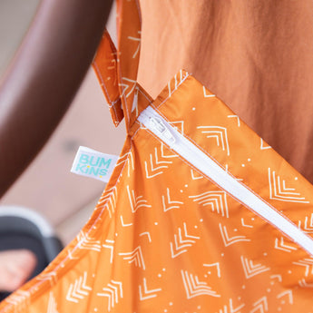 Close-up of Bumkins Wet Bag: Grounded hanging from a stroller handle, with focus on the white zipper.