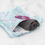 Bumkins Wet Bag: Rainbows holds pink sunglasses, a rolled gray towel, and a book on a marble background.