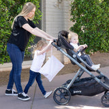 A woman and child push a toddler in a stroller outside by greenery, with a Bumkins Wet Bag: Lace hanging from the handle.