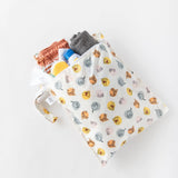Bumkins Wet Bag: Winnie and Friends, filled with toiletries, a small towel, and swim trunks, rests on a white background.