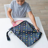 A child places a pink plate into a Bumkins Wet Bag: Super Mario™ Lineup at a white table.