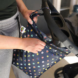 A person zips a Bumkins Wet Bag: Super Mario™ Lineup attached to a stroller handle.