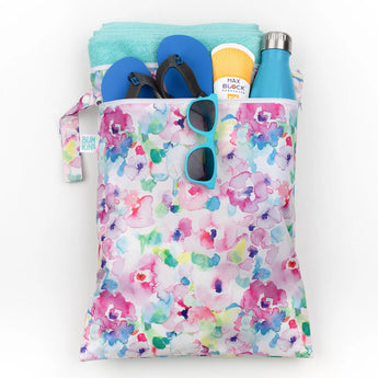 Bumkins Wet/Dry Bag: Watercolor holds shoes, a towel, a water bottle, sunscreen, and sunglasses on a white background.