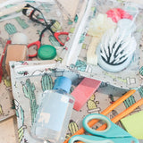 Close-up of Bumkins Clear Travel Bag 3-Pack: Cacti with makeup, hair accessories, and school supplies.