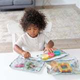 A child sits at a white table with toys in Bumkins Clear Travel Bag 3-Pack: Cacti.