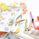 Close-up of colorful crayons and art supplies spilling from a Bumkins Clear Travel Bag 3-Pack: Winnie and Friends on a white background.