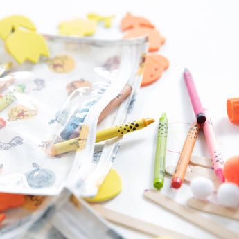 Close-up of colorful crayons and art supplies spilling from a Bumkins Clear Travel Bag 3-Pack: Winnie and Friends on a white background.