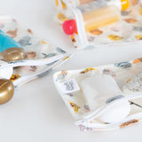 Close-up of Bumkins Clear Travel Bag 3-Pack: Winnie and Friends with TSA-compliant bottles on a white background.