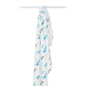 White muslin bamboo swaddle featuring a whales print by Lulujo Inc., hanging on a rod.