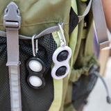 A black and white Simpl Dimpl from Fat Brain Toy Co offers tactile stimulation in a green backpacks gray mesh pocket.