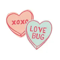 Two candy hearts: an organic XOXO pink and a Finn and Emma blue Love Bug, both colored with eco-friendly dyes.