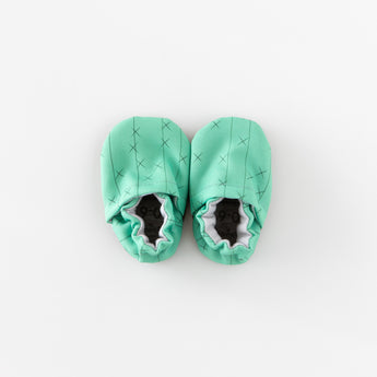 Cabooties Cactus Spines: Mint green baby booties with crisscross stitching and elastic closure, displayed on a white background.