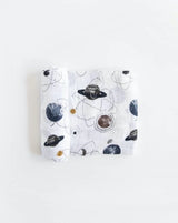 Lightweight cotton swaddle by Little Unicorn with space-themed prints of planets and stars. Folded neatly.