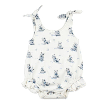 White baby romper from Lovedbaby, with hippo print, tie straps, and ruffled legs. Made of organic cotton.