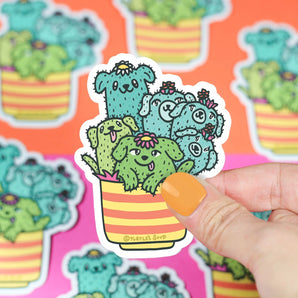 Hand holds a Turtle Soup Vinyl Sticker, Cactus Pups design; cute and durable with more premium vinyls in the background.