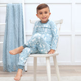 A child smiles in Tesa Babes Wild West Blue PJs while a textured blue blanket drapes over a nearby ladder.
