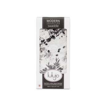 Lulujo Inc.s Bamboo Swaddle with a black floral design is packaged in a windowed box.
