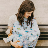 A woman smiles at a child snuggled under a colorful Milk Snob Disney & Pixars Toy Story Cover, ideal for 360° nursing coverage.