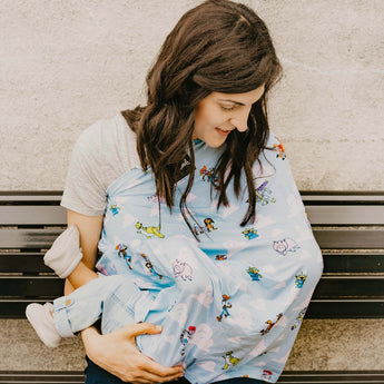 A woman smiles at a child snuggled under a colorful Milk Snob Disney & Pixars Toy Story Cover, ideal for 360° nursing coverage.