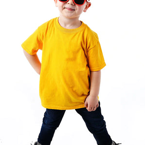 A child in a yellow shirt, dark jeans, and Sunstaches Lil Characters Mickey Mouse Sunglasses smiles confidently on a white background.