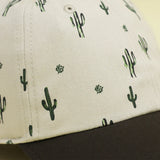 Close-up of Storied Hats Cactus Sunset organically-made hat with cactus patterns and black curved brim.
