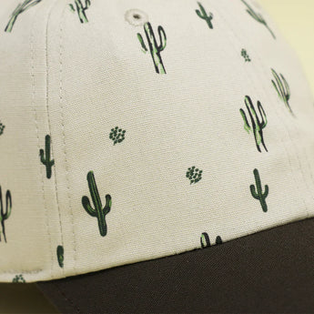 Close-up of Storied Hats Cactus Sunset organically-made hat with cactus patterns and black curved brim.