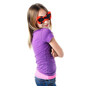 A girl in Sunstaches Lil Characters Miraculous Lady Bug sunglasses and a purple shirt poses confidently with arms crossed.
