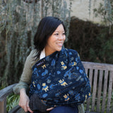 A woman smiles on a bench with Milk Snobs Cover Disneys Winnie the Pooh, surrounded by lush greenery.