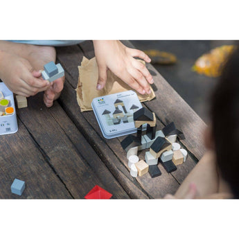 Kids assemble shapes from the eco-friendly PlanToys Construction Set on wood, guided by a card.
