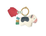 Itzy Pal Cow: red silicone barn and white & gray plush cow attached to tan silicone ring with cream & green striped fabric.