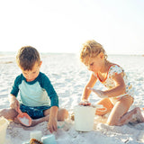 Two kids focus intently on their sandcastle using the Emerson and Friends Beach Bucket Toy Play Set under the sunny sky.