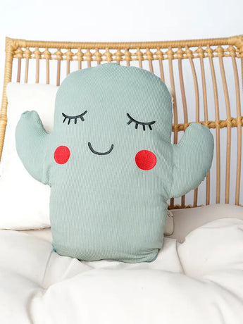 The Bamboo Pillow, Cactus by Emerson and Friends sits on a chair, ultra-soft with Poly-fil stuffing, featuring a smiley face and red cheeks.